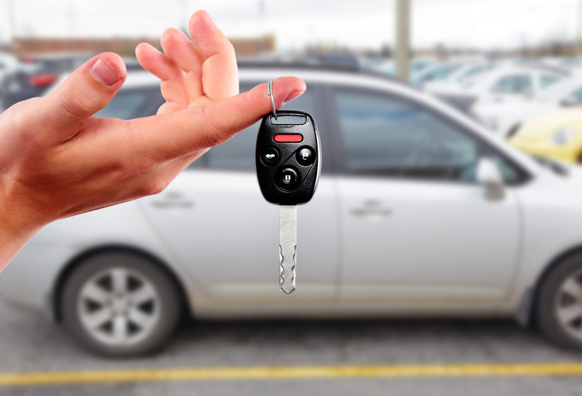 Car dealer hand with key. Auto dealership and rental concept background.